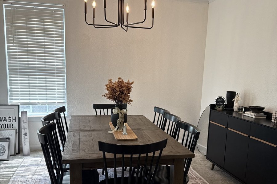 A finished dining room with a black chandelier and matching dining set