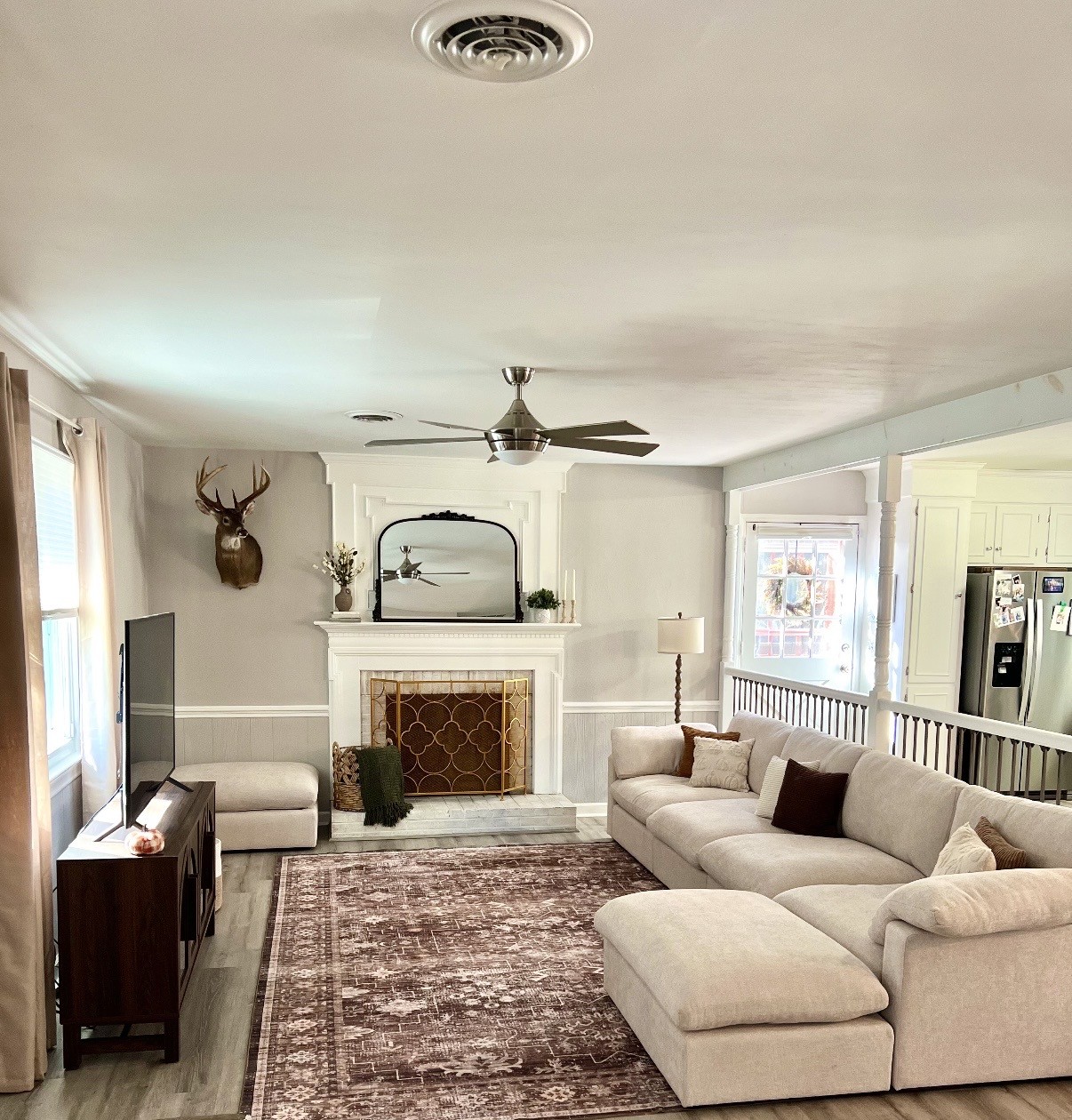 A finished living room with a cream sectional and a styled fireplace mantel